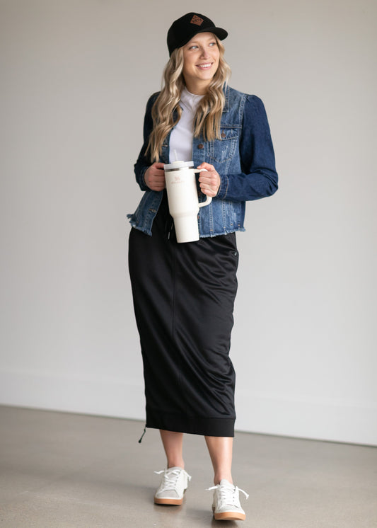 A black midi skirt with a drawstring waist, ribbed hem, pockets, and bottom side zipper.