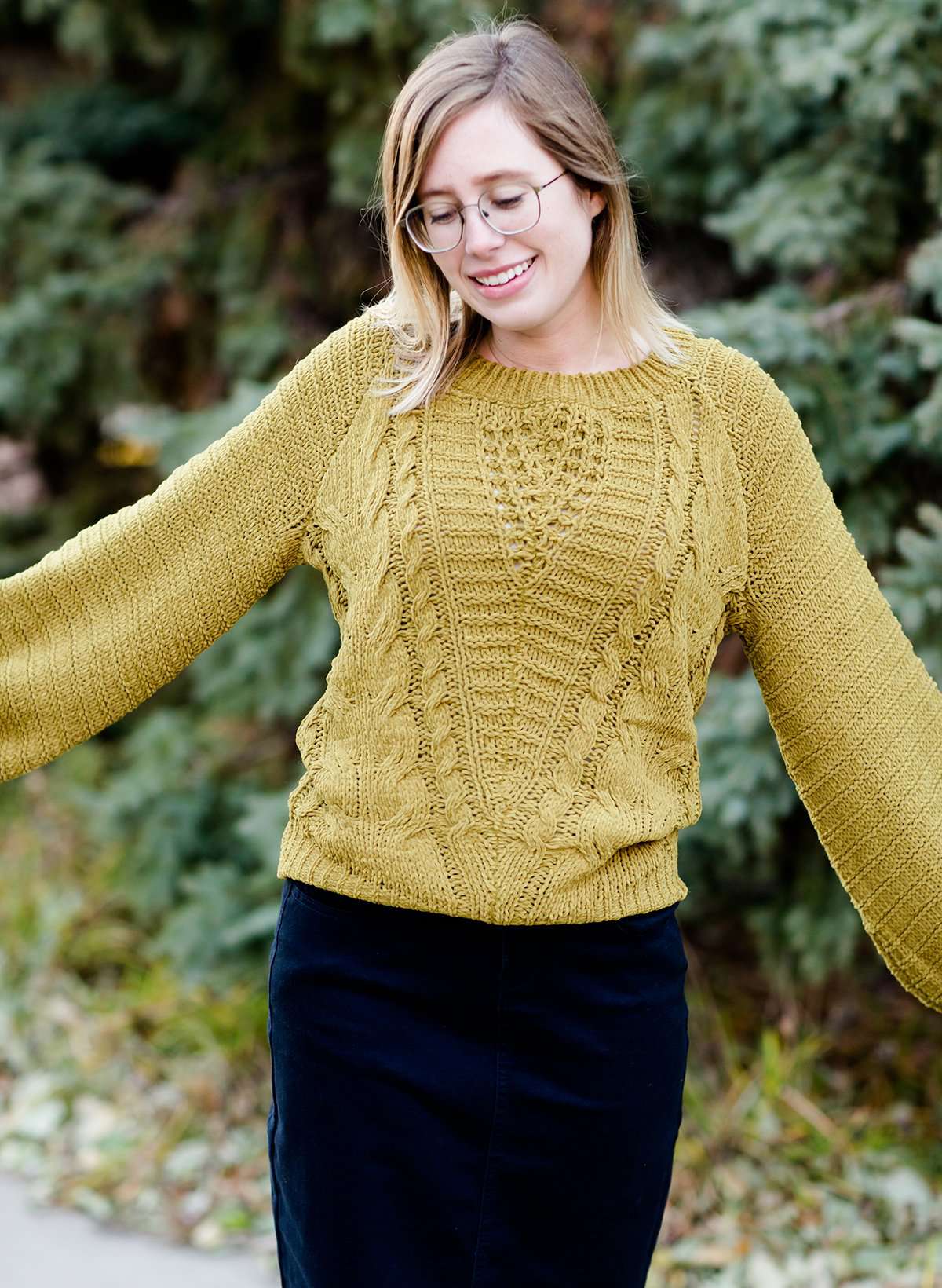 Young woman wearing a balloon sleeve chenille like sweater with a below the knee navy midi skirt