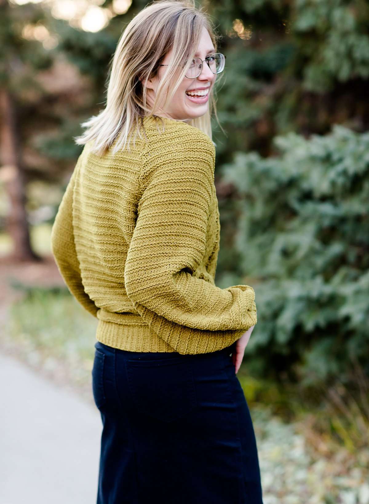 Young woman wearing a balloon sleeve chenille like sweater with a below the knee navy midi skirt