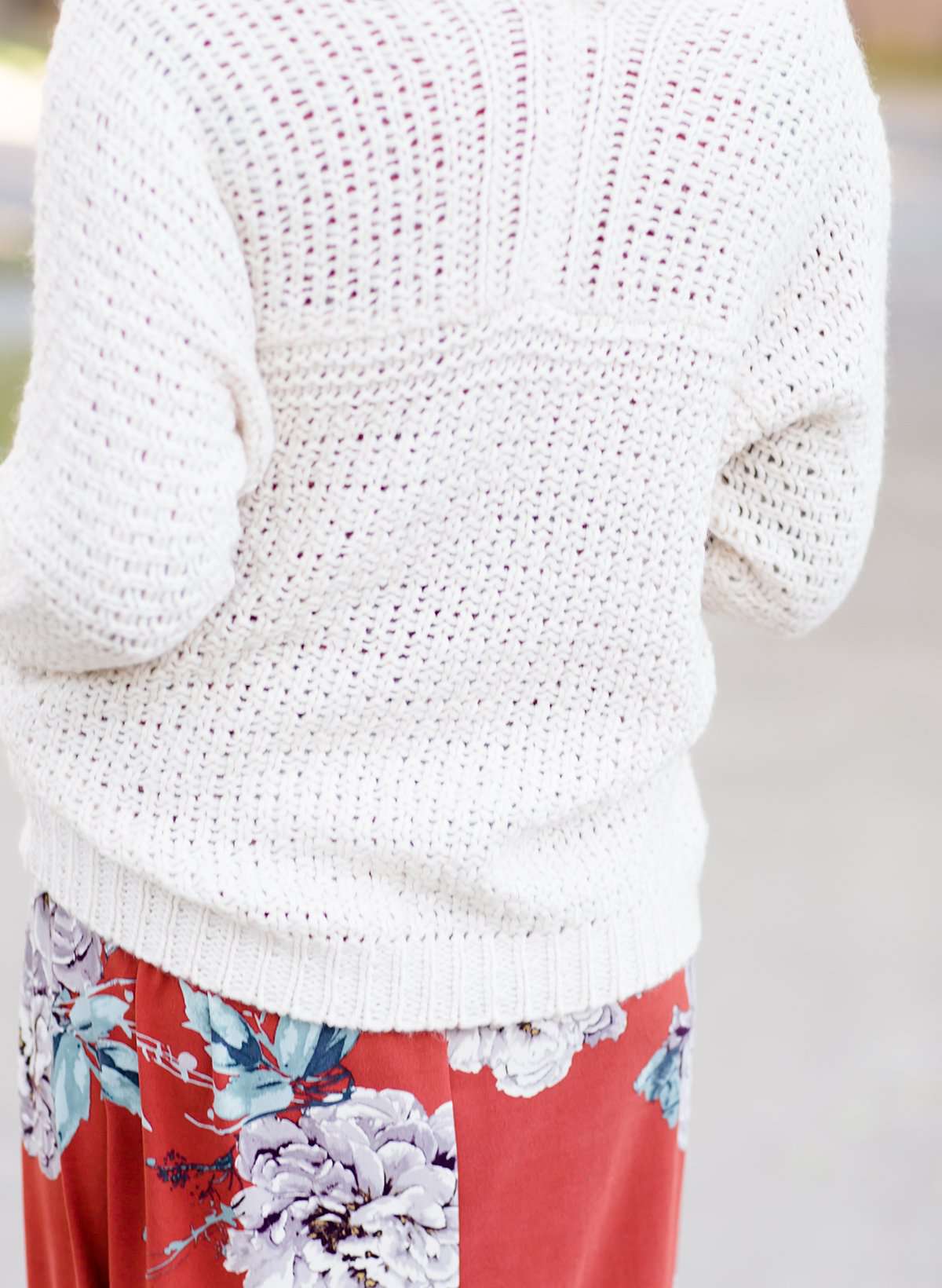 Young woman wearing a ivory chunky knit acrylic and wool sweater. This sweater has front pockets and features an open front.