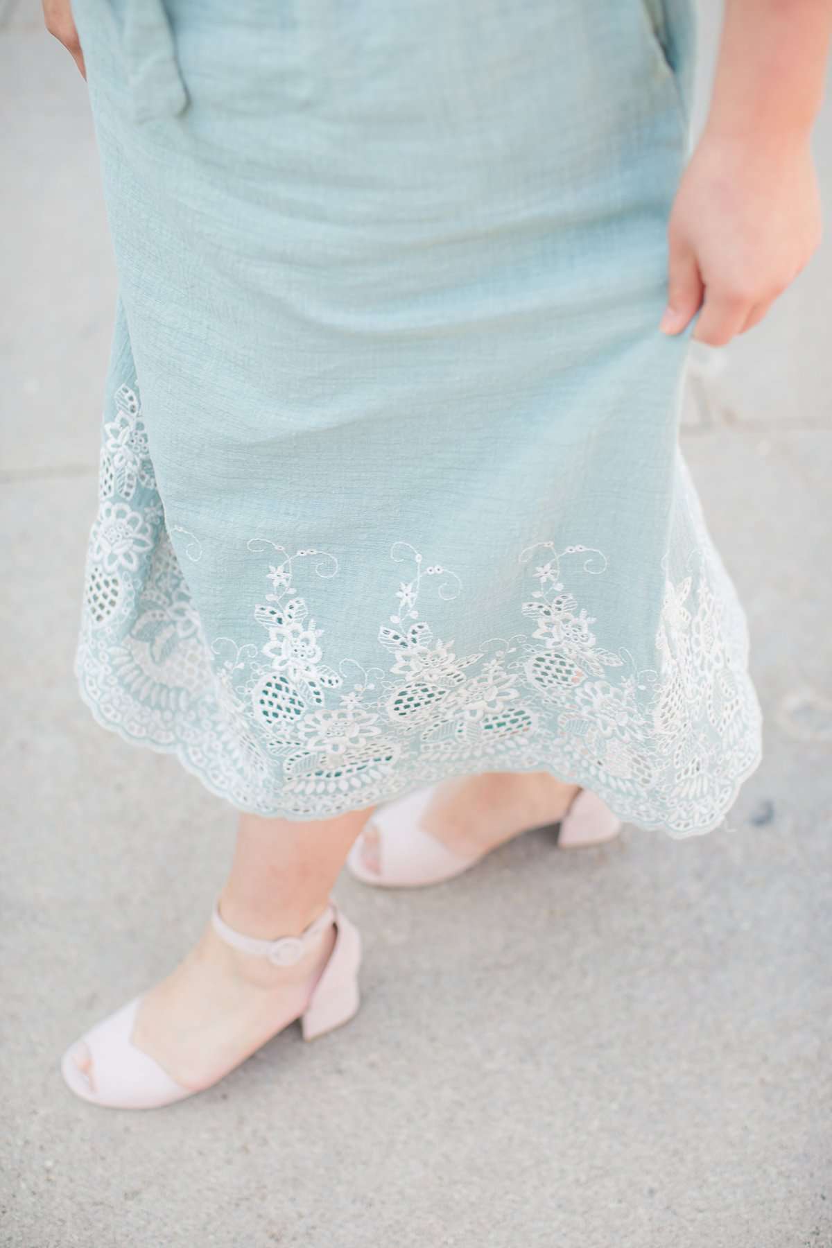 Woman wearing a mint green cotton midi skirt with a self tie and feminine crochet lace detail at the bottom hem