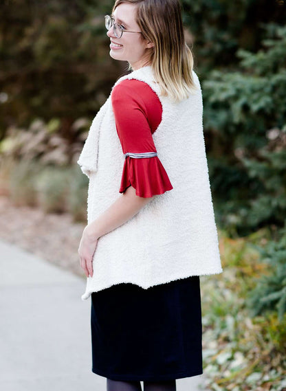 Young woman in a modest black midi skirt wearing a cream colored, soft drape style vest.