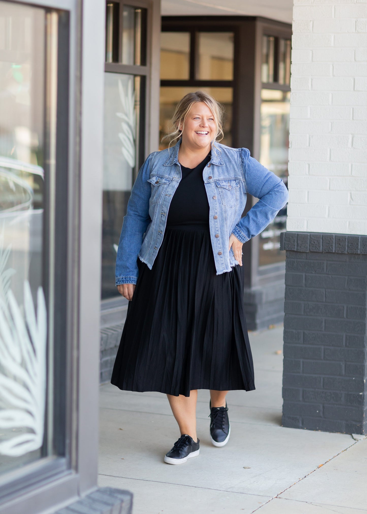 A knit and elevated black midi dress with a pleated skirt and a comfortable fit.