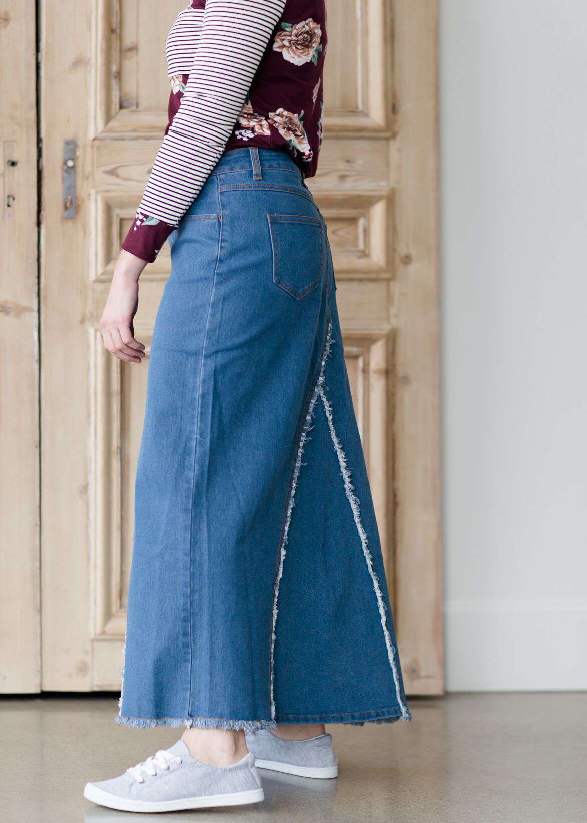 woman wearing an a-line modest long denim skirt with fringe detail and no slit