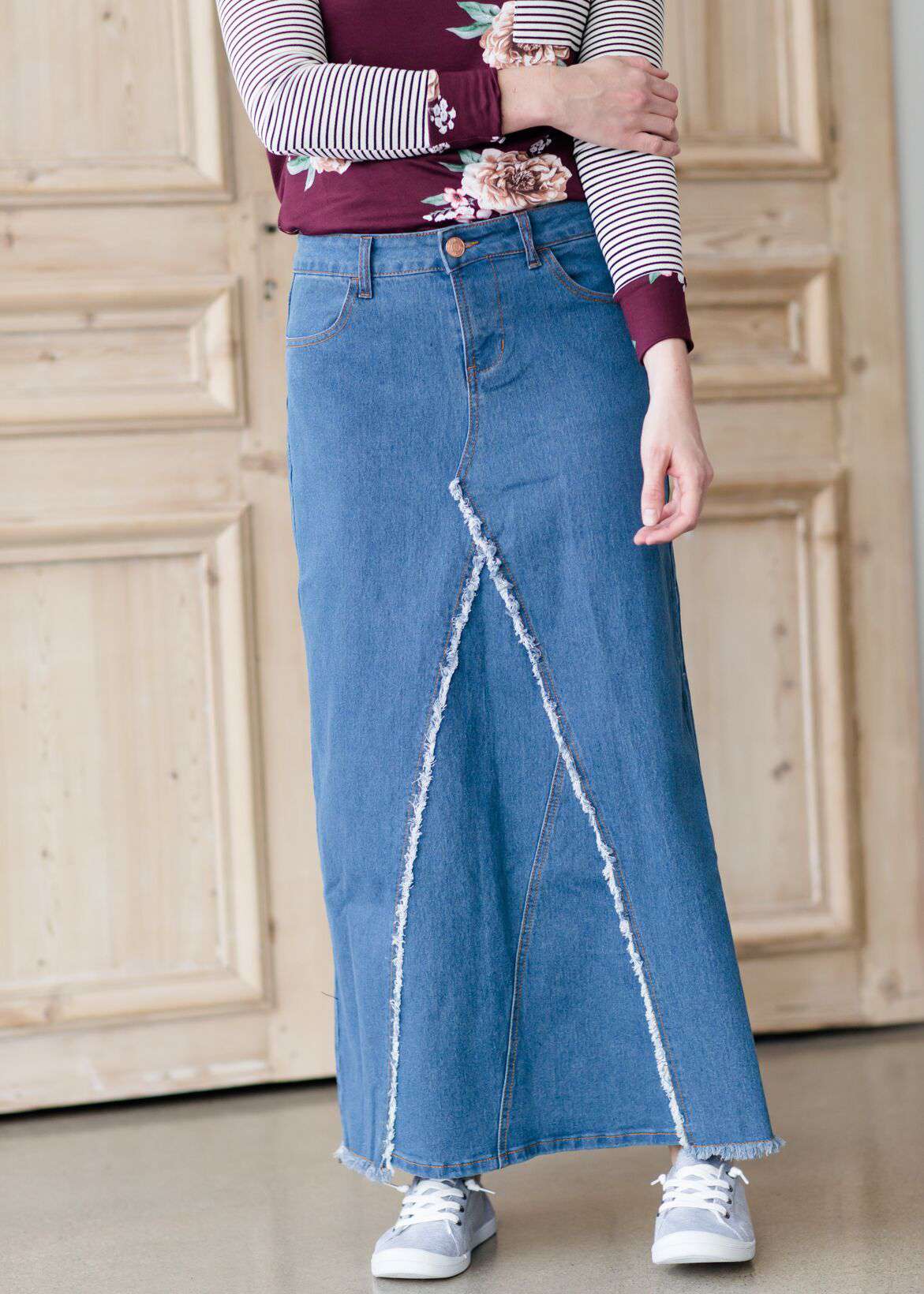 woman wearing an a-line modest long denim skirt with fringe detail and no slit