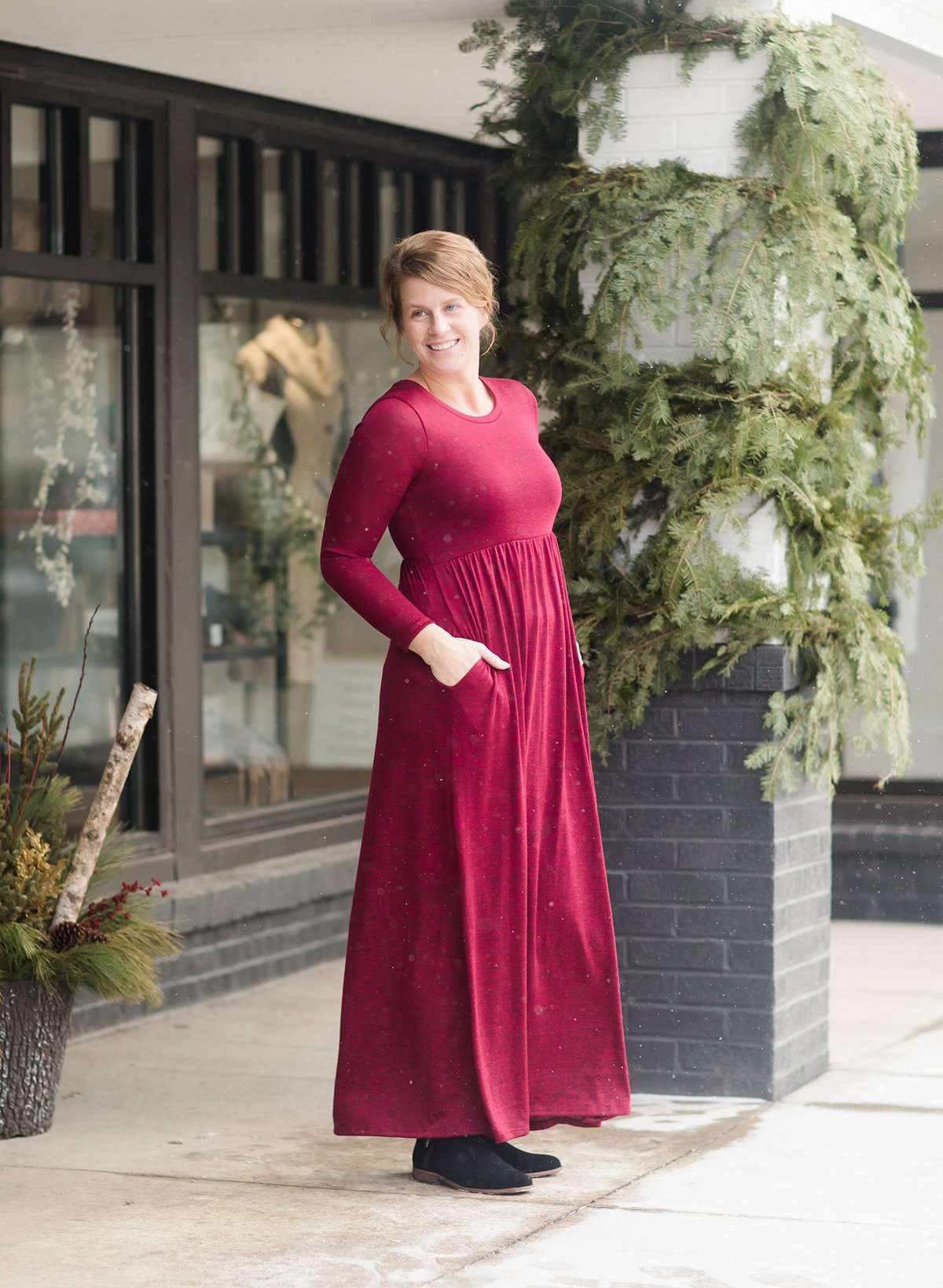 Woman wearing a wine colored maxi dress made of a hacci material standing outside of Inherit Clothing Company