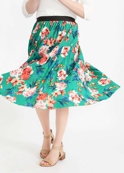 Woman wearing an emerald green floral stretchy pleated swing skirt with dress shoes and a white lace top