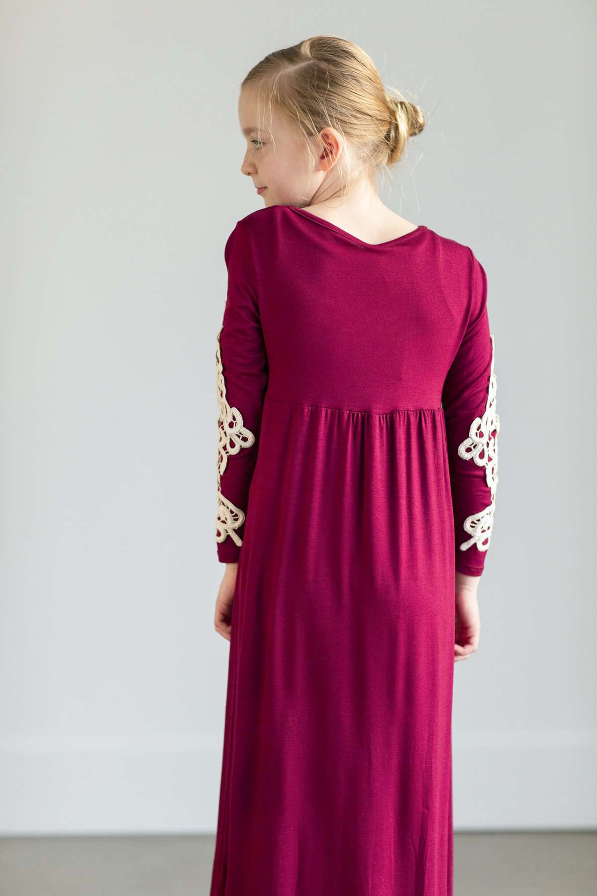 Young girl wearing a burgandy maxi dress with crochet detail.