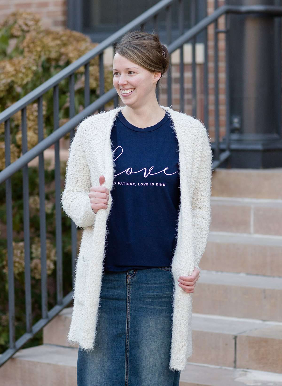 Young woman wearing a love is patient king james version bible verse graphic navy tee