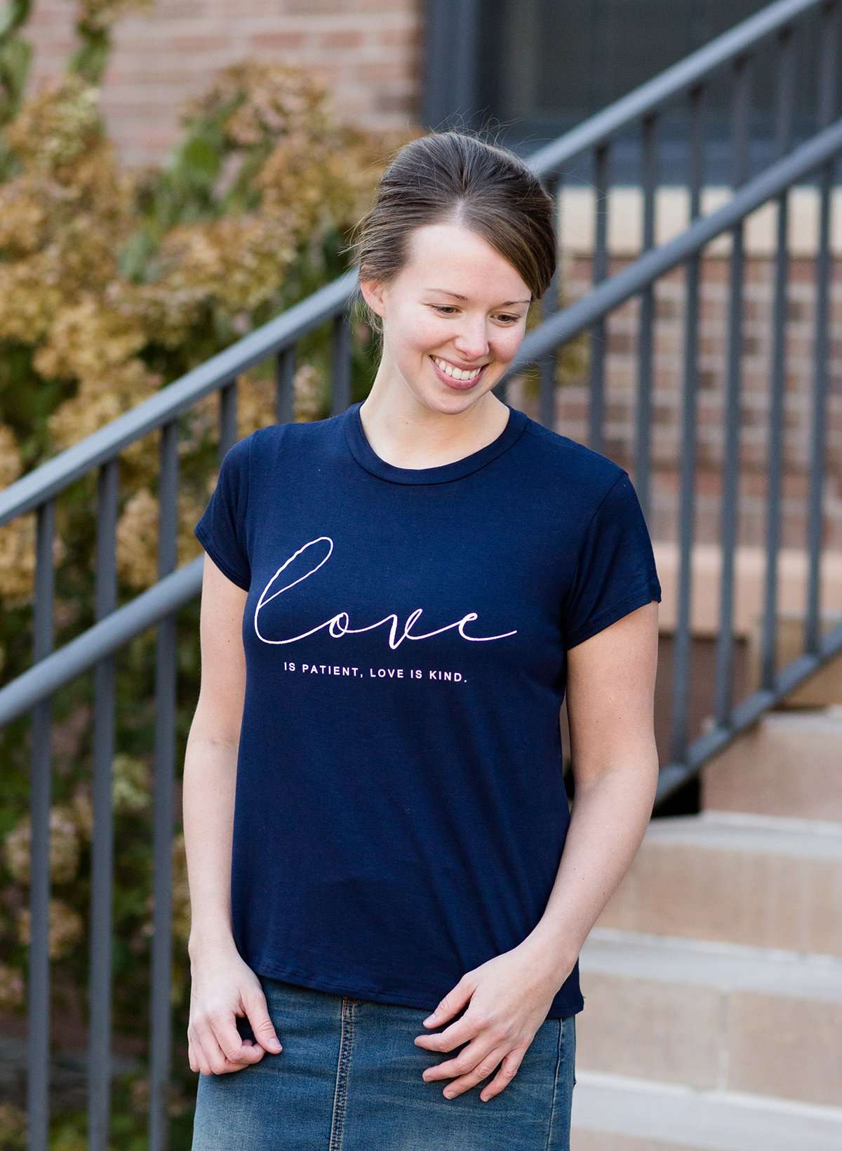 Young woman wearing a love is patient king james version bible verse graphic navy tee