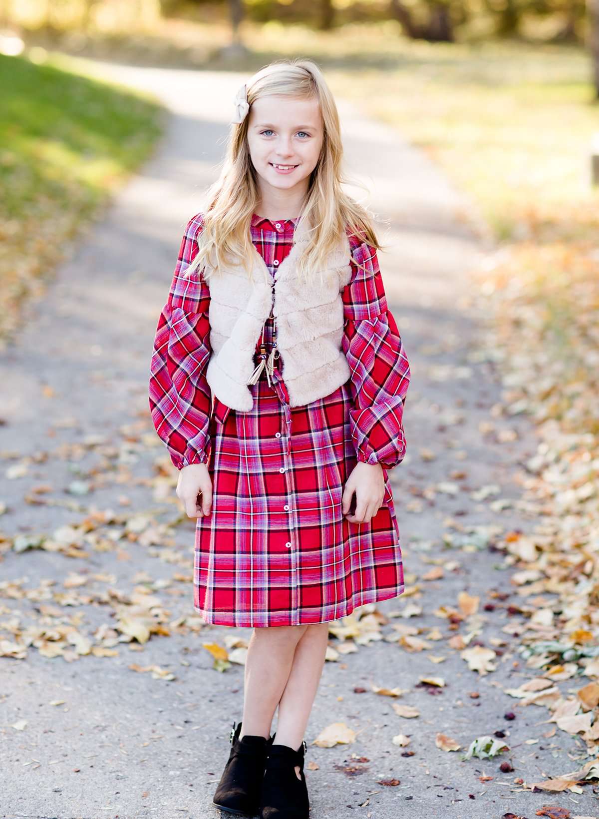 Young girl wearing a modest red plaid midi dress with balloon style sleeves. This dress also features a self tie fabric waist and is lined.