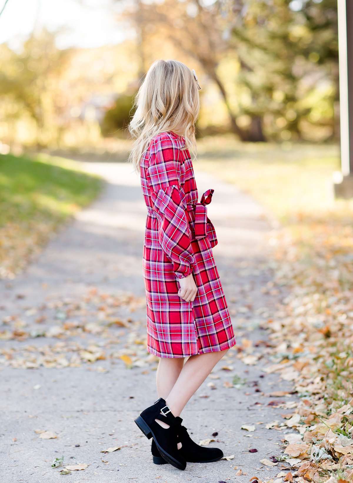 Young girl wearing a modest red plaid midi dress with balloon style sleeves. This dress also features a self tie fabric waist and is lined.