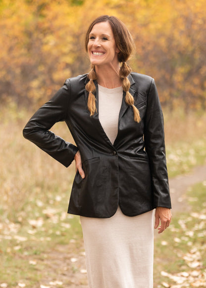 The Sandelle Faux Leather Blazer is a closet must-have! It is designed in a soft and supple vegan black leather fabric for elevated style. It has a one button closure in the center, a classic lapel collar, and it hits right below the hips for added modesty. There are functional front pockets at the waist to hold your essentials. The fit of this blazer is relaxed yet classy perfect over a dress or skirt and sweater! You will have so many outfit options with just this one layer! 